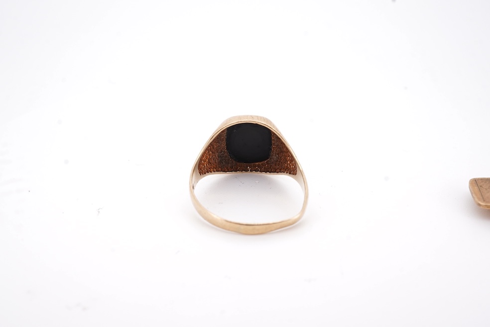 A 1980's 9ct gold tie clip, 39mm and a similar 9ct gold and black onyx set signet ring, gross weight 10 grams.